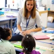 A teacher in the classroom talking to two students.