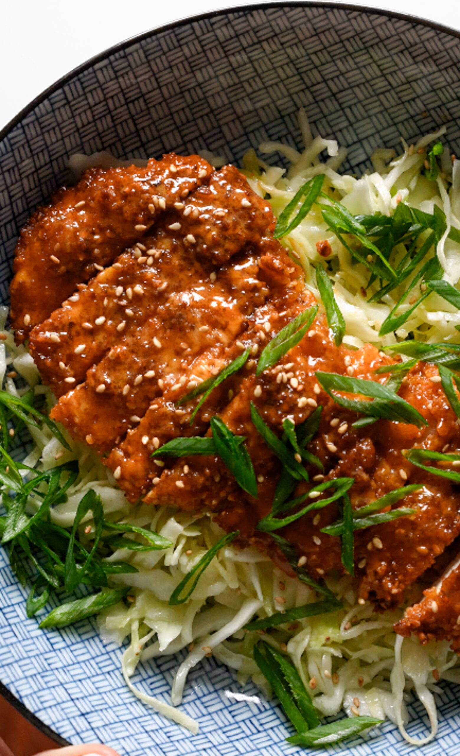 Crispy Gochujang Chicken on a bed of thinly sliced cabbage with green onions